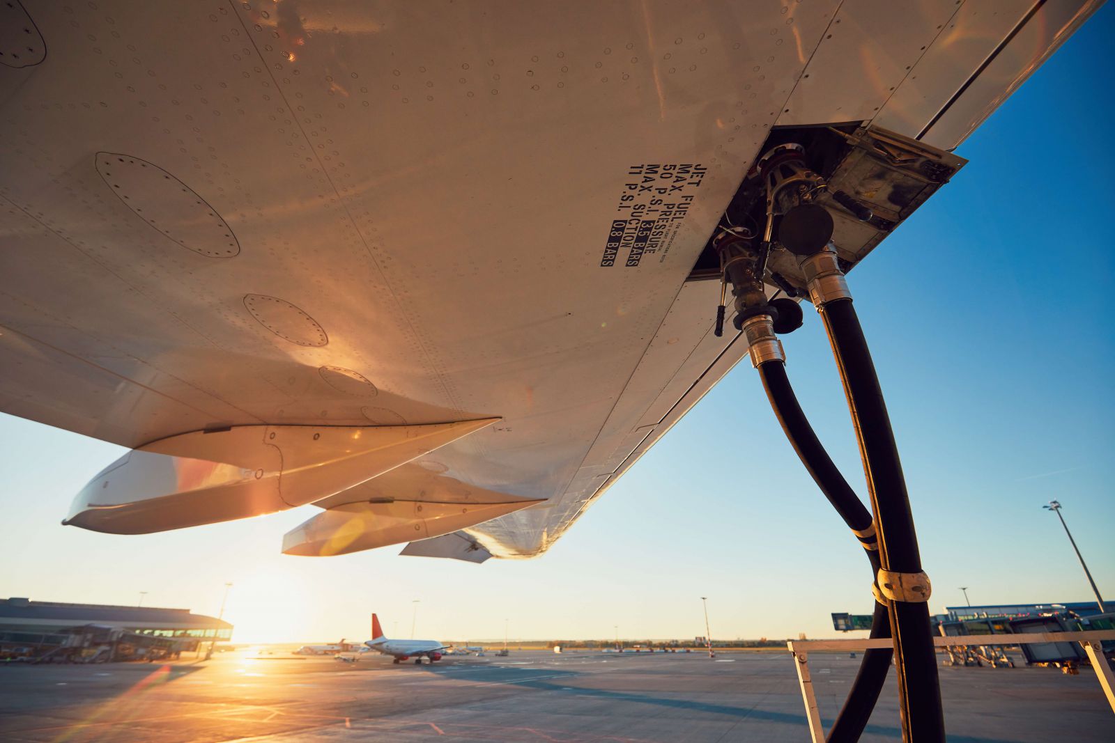 Refueling of an airplane before flight with a sunset in the background.