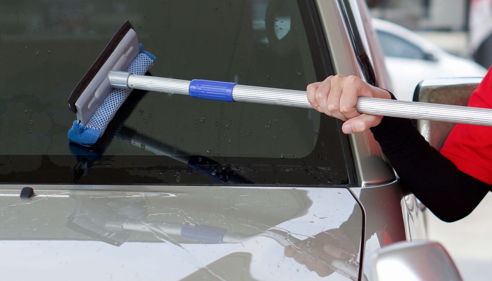 Gas station worker cleaning the car windshield with window squeegee