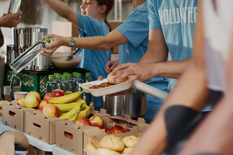 Hands placing food into a box, showcasing Sunoco's partnership with Philabundance to end hunger.