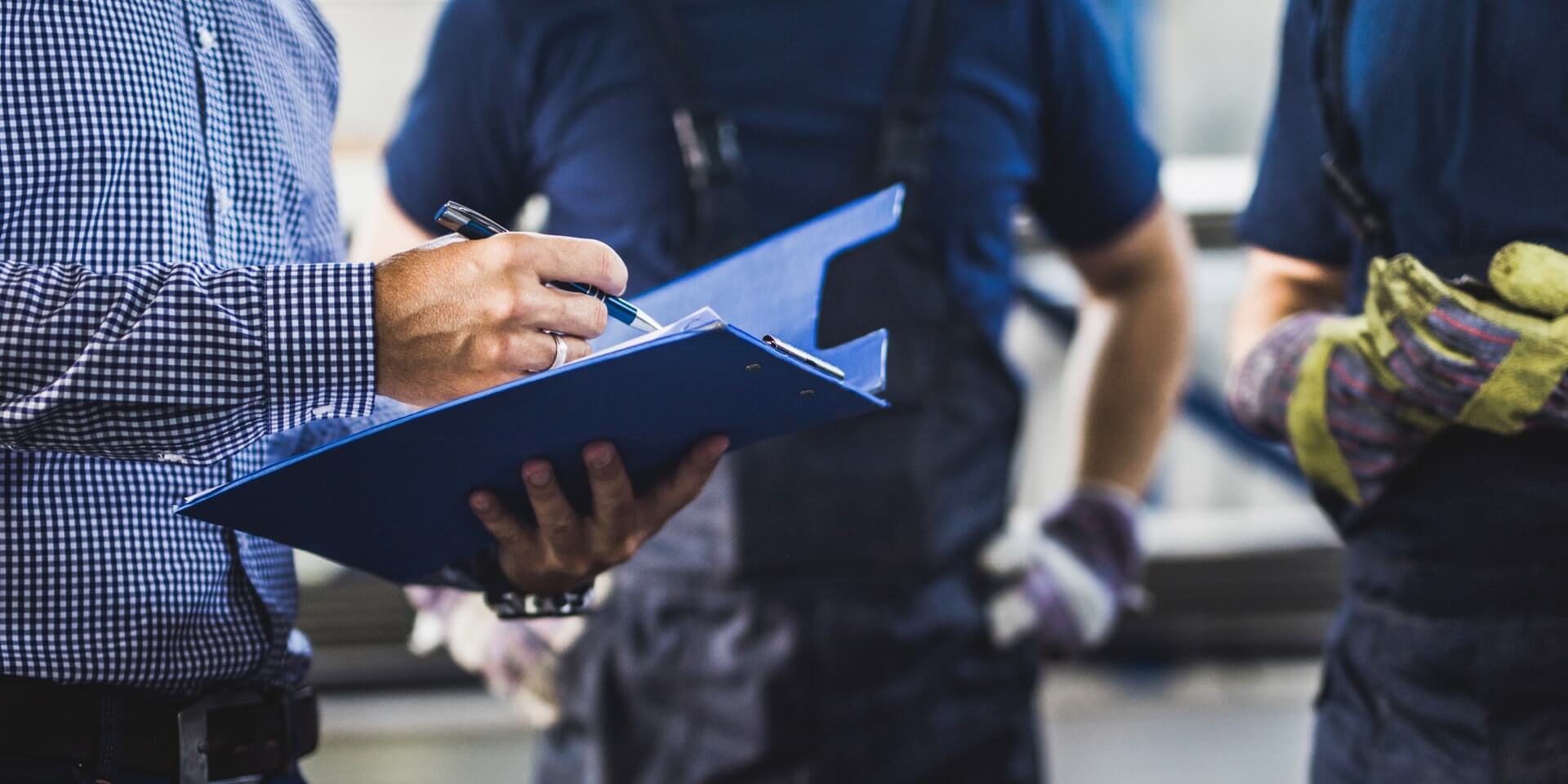 Man with clipboard and two workers