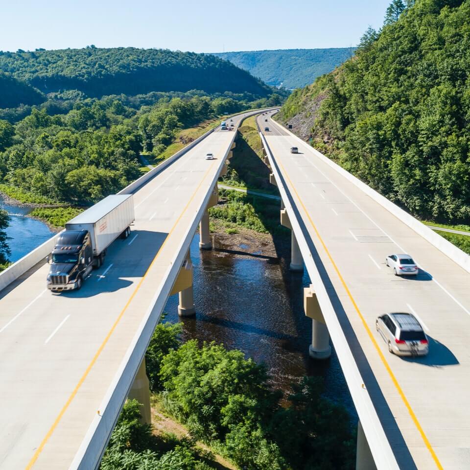 Cars and trucks driving on overpass over river